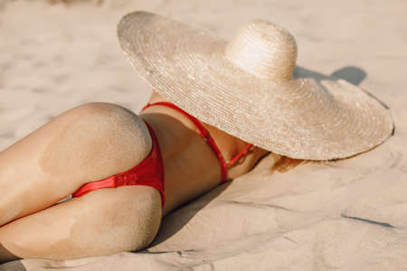 Young attractive woman in bikini with big straw hat posing at sandy beach. Girl at vacationsの写真素材