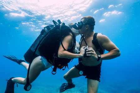 August 20, 2020. Anapa, Russia. Happy couple of scuba divers kiss underwater in transparent blue sea. Scuba diving in oceanのeditorial素材