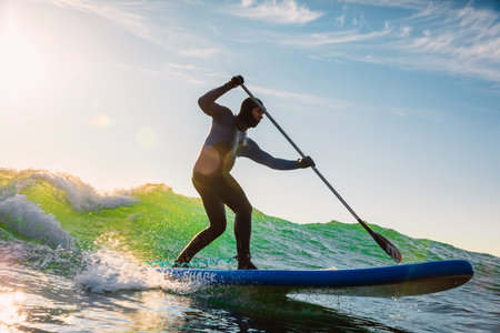 December 8, 2020. Anapa, Russia. Stand Up Paddle surfing on waves. Surfer in wetsuit with paddle ride on sea waveのeditorial素材