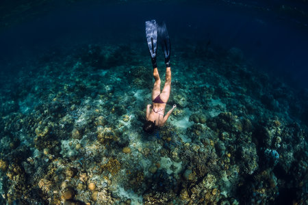 Woman swim underwater with fins. Freediving in blue oceanの写真素材
