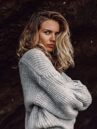 Attractive cheerful woman in sweater posing at black sand beach in Baliの写真素材