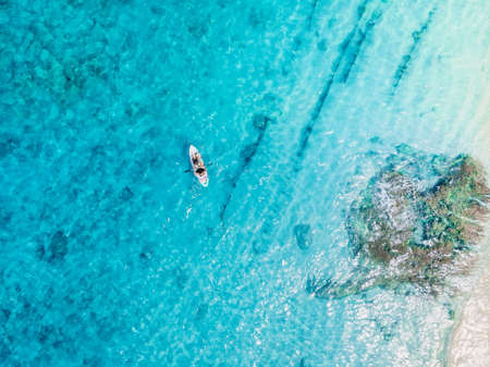 Aerial view with surfer paddle on surfboard in ocean. Top view