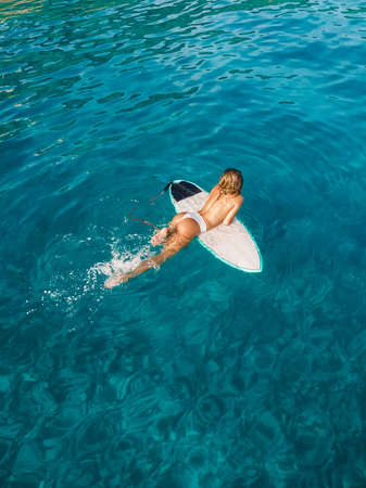 Naked surfer woman with surfboard on tropical beach. Harmony with nature