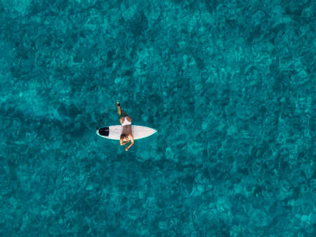 Naked surfer woman with surfboard on tropical beach. Harmony with natureの写真素材