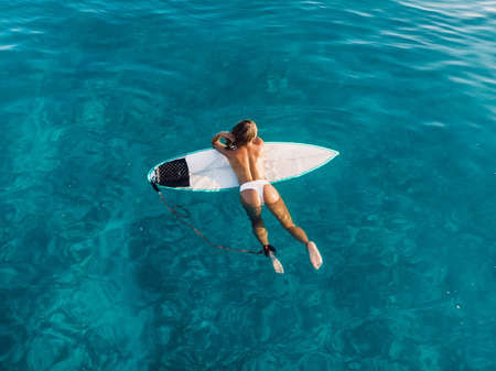 Naked surfer woman with surfboard on tropical beach. Harmony with nature