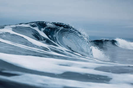Perfect ocean waves with blue water cloudy dark sky.の写真素材