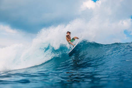 January 21, 2021. Bali, Indonesia. Caucasian young surfer ride at ocean wave on the surfboard.