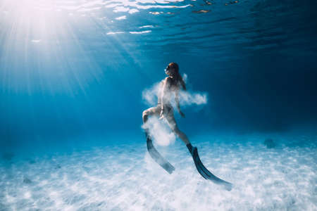 Freediver woman swim over sandy sea with United States flag.