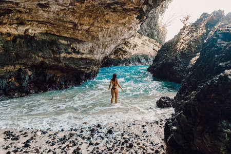 Slim brunette woman in bikini posing at sandy beach. Tanned female model at vacationsの写真素材