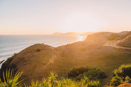 Coastline with ocean and hills at warm sunset or sunriseの写真素材