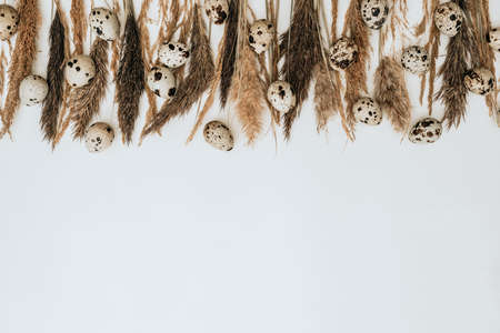 Reeds foliage branches bouquet with eggs on white background. Flat lay, top view. Easter conceptの写真素材