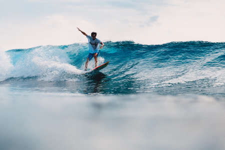 March 11, 2021. Bali, Indonesia. Surfer on surfboard and blue wave. Woman in ocean during surfing.のeditorial素材