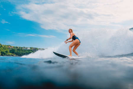 March 11, 2021. Bali, Indonesia. Surfer on surfboard and blue wave. Woman in ocean during surfing.のeditorial素材