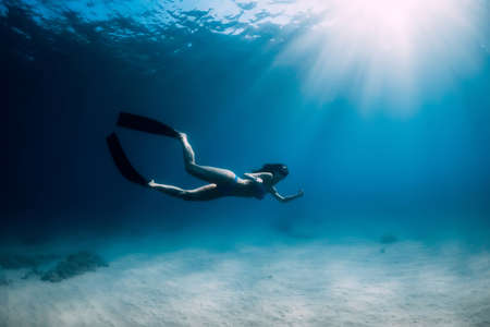Freediver woman holding sand in hands underwater. Freediving in tropical blue oceanの写真素材