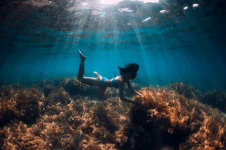Freediver woman holding sand in hands underwater. Freediving in tropical blue oceanの写真素材