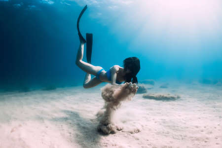 Freediver woman holding sand in hands underwater. Freediving in tropical blue oceanの写真素材