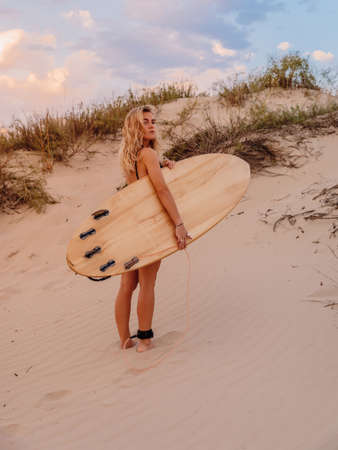 Surfer girl with surfboard on beach and warm sunset colors. Attractive surfer womenの写真素材