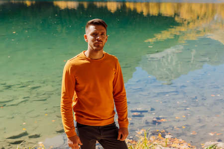 Hiker man at the crystal lake in autumnal mountains. Mountain lake and hiker travelerの写真素材
