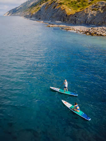 June 13, 2021. Anapa, Russia. Couple on stand up paddle board at quiet sea. People traveling on...