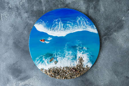 Resin art round painting. Epoxy art composition with blue ocean waves, boat and stone beach. Flat...