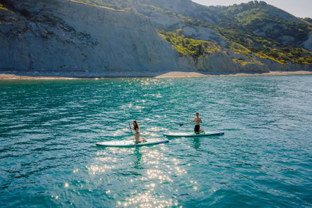 May 28, 2021. Anapa, Russia. Couple traveling on stand up paddle board at sea. People walking on Red...