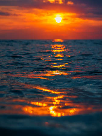 Sunset with clouds, warm colors and waves in ocean.の写真素材