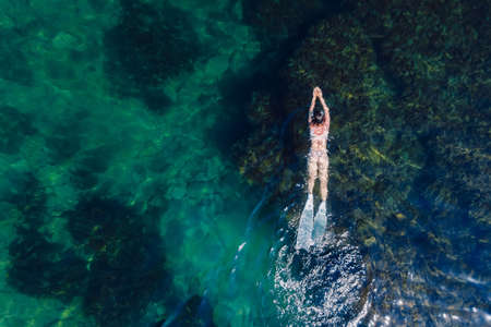 Free diver woman with freediving fins swim in blue ocean. Aerial viewの写真素材