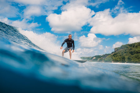 April 04, 2021. Bali, Indonesia. Surfer male ride on surfboard at blue ocean wave.のeditorial素材