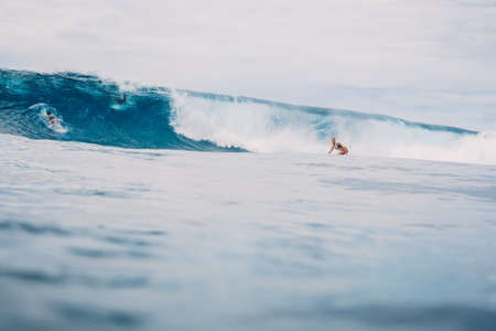 April 04, 2021. Bali, Indonesia. Surfer male ride on surfboard at blue ocean wave.