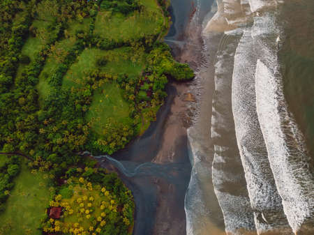 Aerial view of volcanic sand beach with river, ocean and waves in Balian, Baliの写真素材