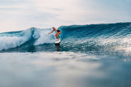 Surfgirl at surfboard and perfect barrel wave. Sporty woman during surfing in Bali.