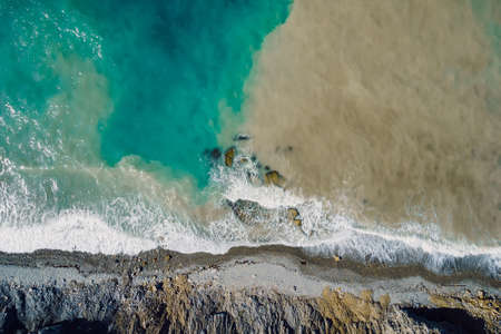 Aerial view of ocean surface with waves, dirty water and coastlineの写真素材