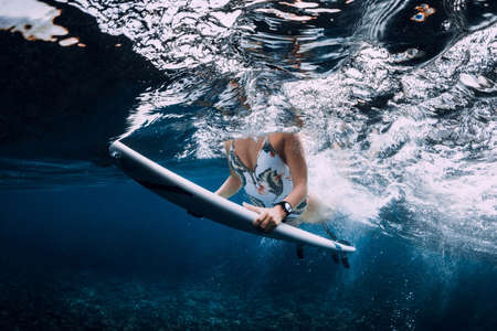 Surfer girl with surfboard dive underwater with under ocean wave.の写真素材