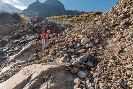 Hiker sporty woman with backpack in the mountains. Mountain with glacier and traveler