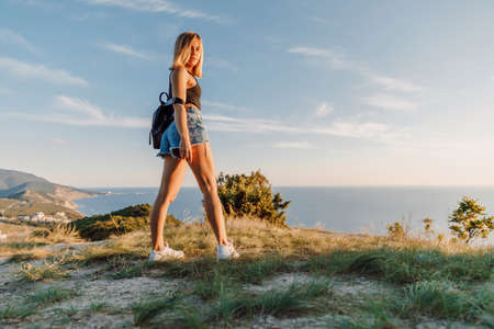 Attractive woman relaxing in nature with warm sunset. Young girl in the mountainsの写真素材