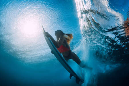 Surfer girl with surfboard dive underwater with big ocean wave at blue ocean.の写真素材