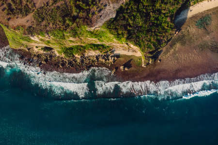 Tropical ocean with waves and surfer in Bali. Aerial view at Balangan beach.