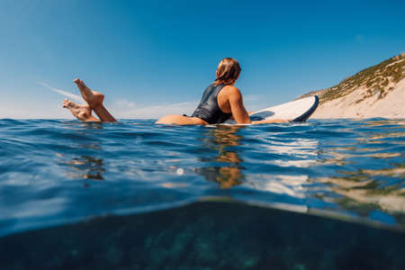 Sunny day with attractive surf girl on surfboard in ocean. beautiful woman look at camera