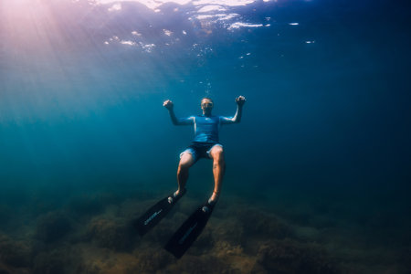 August 07, 2021. Varna, Bulgaria. Sporty woman with freediving fins posing underwater in ocean with sunlight. Young girl in colorful bikini glides underwater.の写真素材