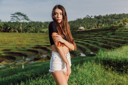 Beautiful young woman on rise terraces with morning sun light in tropical Bali islandの写真素材