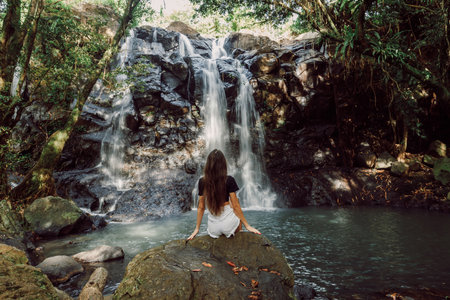 Traveller woman sitting on stone and waterfall in Baliの写真素材