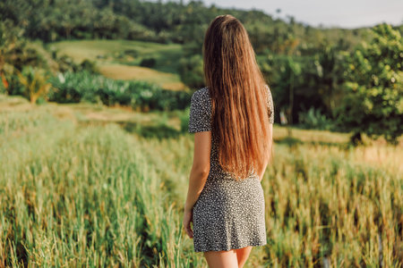 Woman with beautiful hairs walk on rise terraces in tropical Bali island with morning sun lightの写真素材