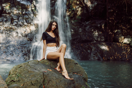 Beautiful young woman posing on waterfall in tropical Baliの写真素材