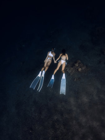 Girls freedivers dive together in deep ocean corals. Freediving with couple in underwaterの写真素材