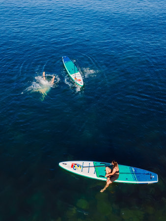 July 24, 2022. Antalya, Turkey. Couple relax and swim on stand up paddle board at blue sea. People on Red paddle sup board in Mediterranean sea. Aerial viewのeditorial素材