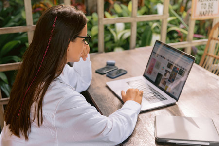 Attractive young business woman working on laptop computer in summer cafe