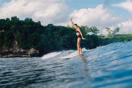 April 20, 2023. Bali, Indonesia. Smiling surfer girl on surfboard. Woman in ocean during surfing. Surfer on waveのeditorial素材
