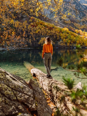 Woman at crystal lake in the autumnal mountains. Mountain lake and travellerの写真素材