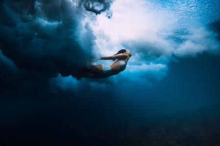 Woman swim underwater with breaking wave with foam in transparent ocean.の写真素材