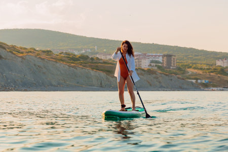 July 30, 2022. Dalaman, Turkey. Young woman rowing on SUP board at sea with beautiful landscape.のeditorial素材